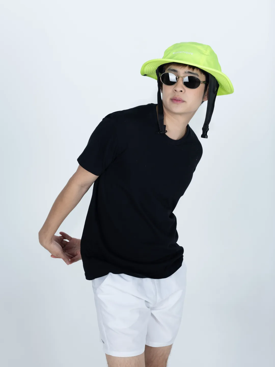 A man in a neon lime AQUATIQUE bucket hat, sunglasses and a black T-shirt